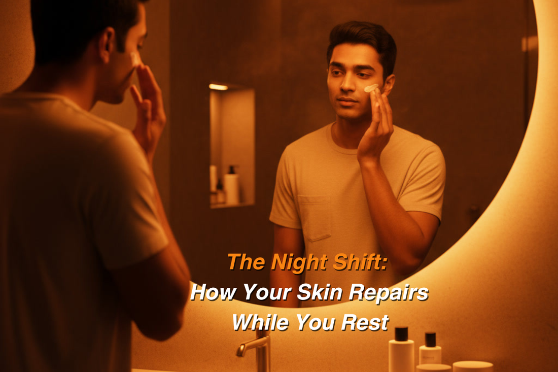 Indian man applying night cream while looking into a bathroom mirror under warm orange lighting; minimal skincare bottles placed on the counter.